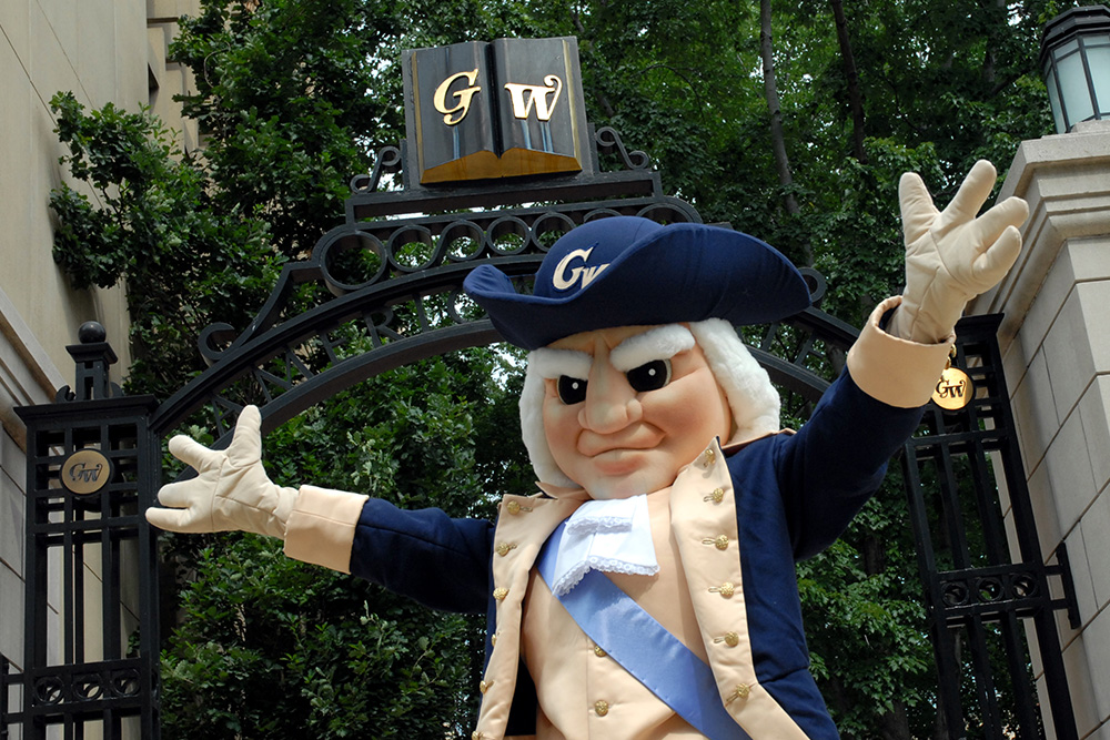 The mascot George throws his arms up in excitement outside of America's Gate on the Foggy Bottom campus