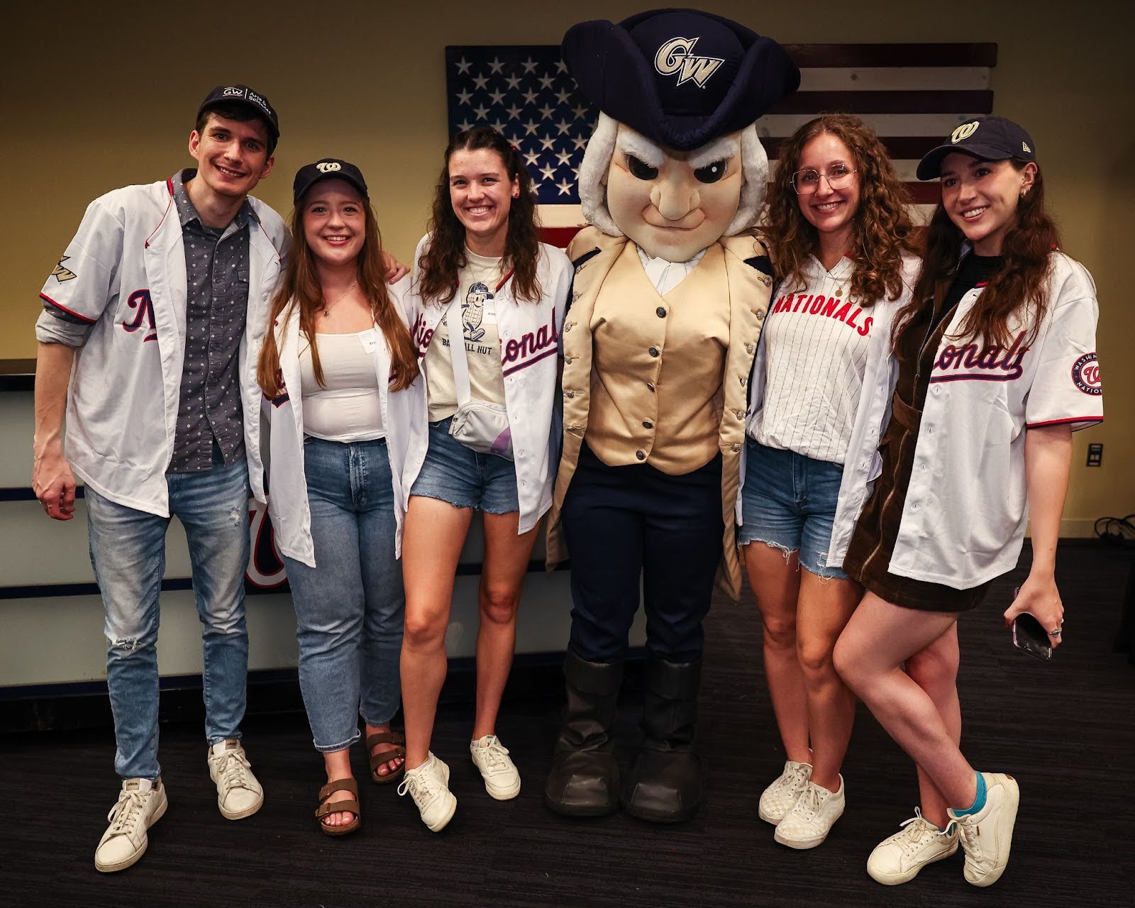 Recent alumni pose with George the mascot at a Washington Nationals game